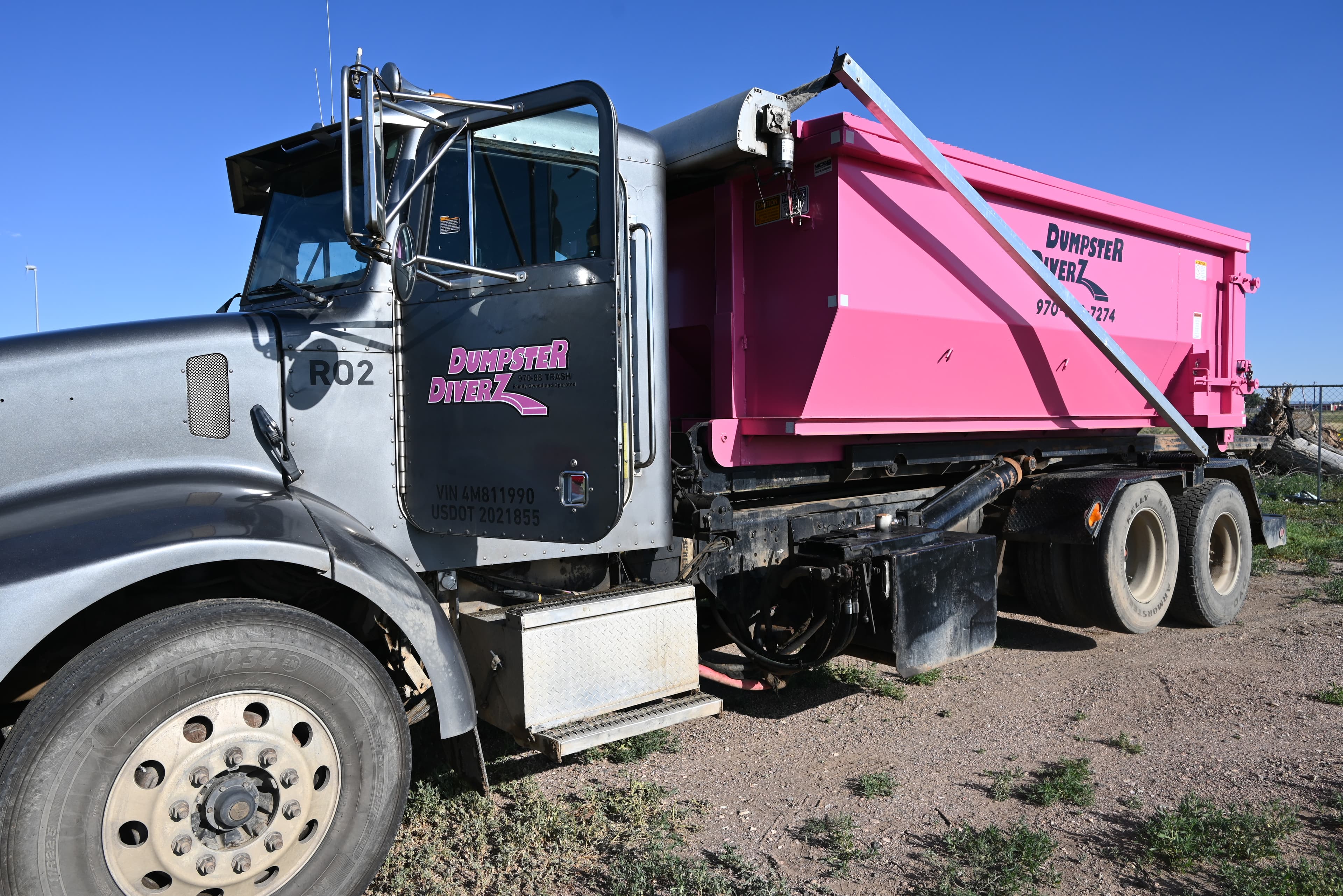 Dumpster Diverz branded truck and pink roll-off dumpster